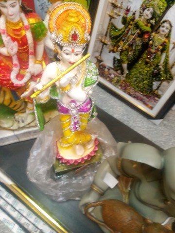 Krishna idol showpiece displayed on glass shelf